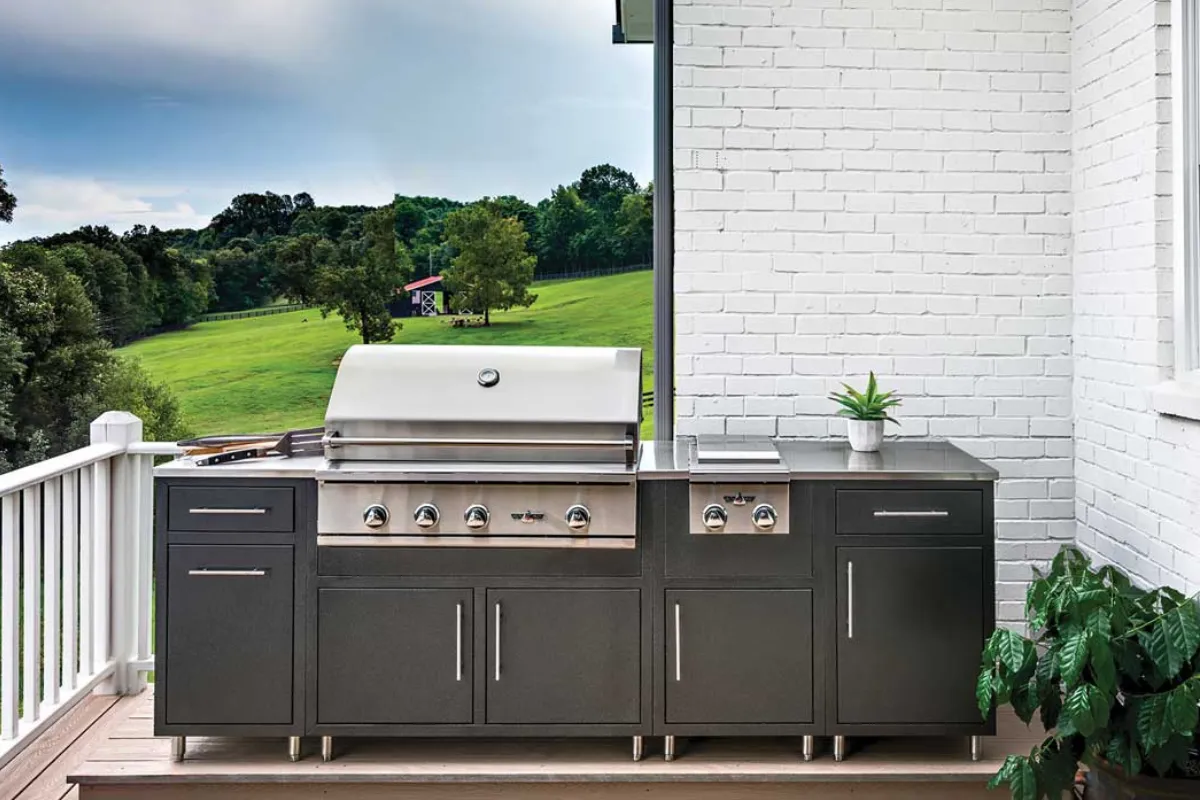 An outdoor kitchen with weather resistant cabinetry and a built-in grill under a covered patio