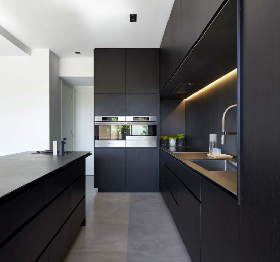 A contemporary Euro frameless kitchen in matt black with an integrated handle profile and under-cabinet lighting