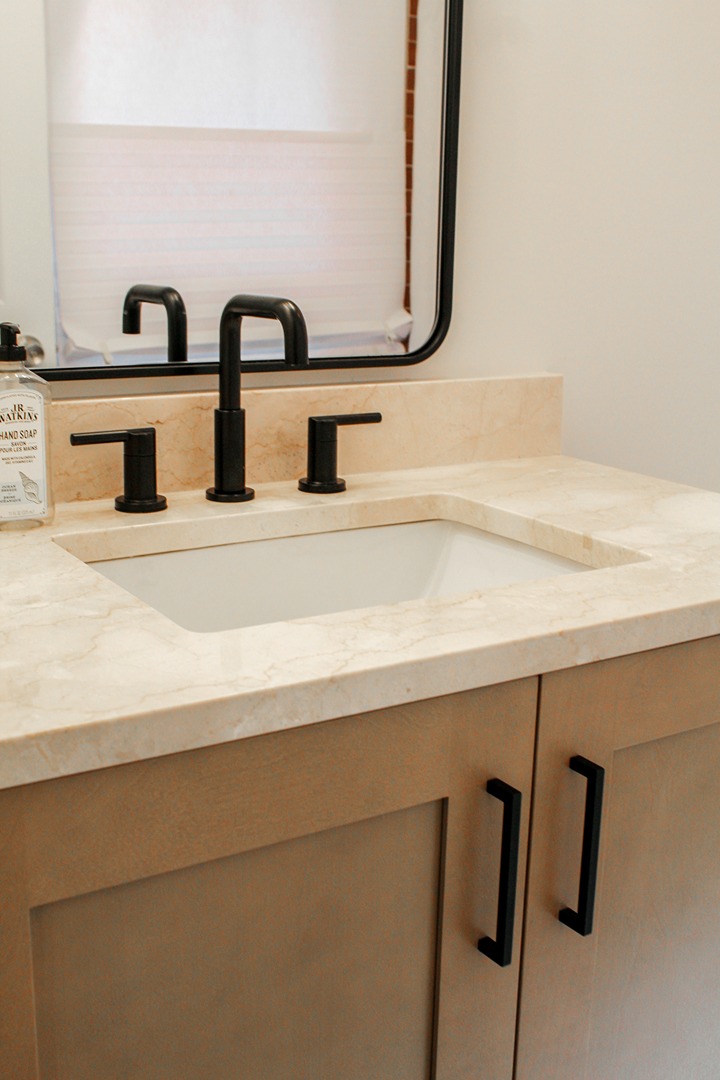 A close-up of a stone vanity top with matt black hardware on a Tiger Cabinetry bathroom cabinet