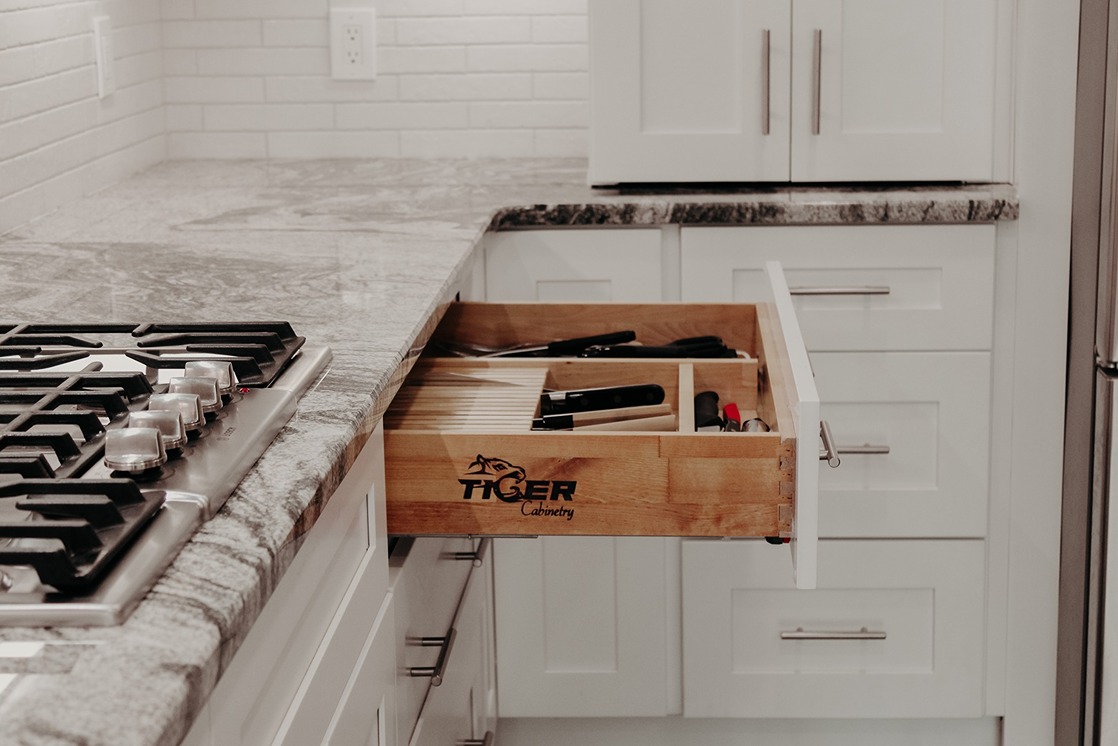 A Tiger Cabinetry installer fitting a run of white wall cabinets during a Nashville kitchen installation