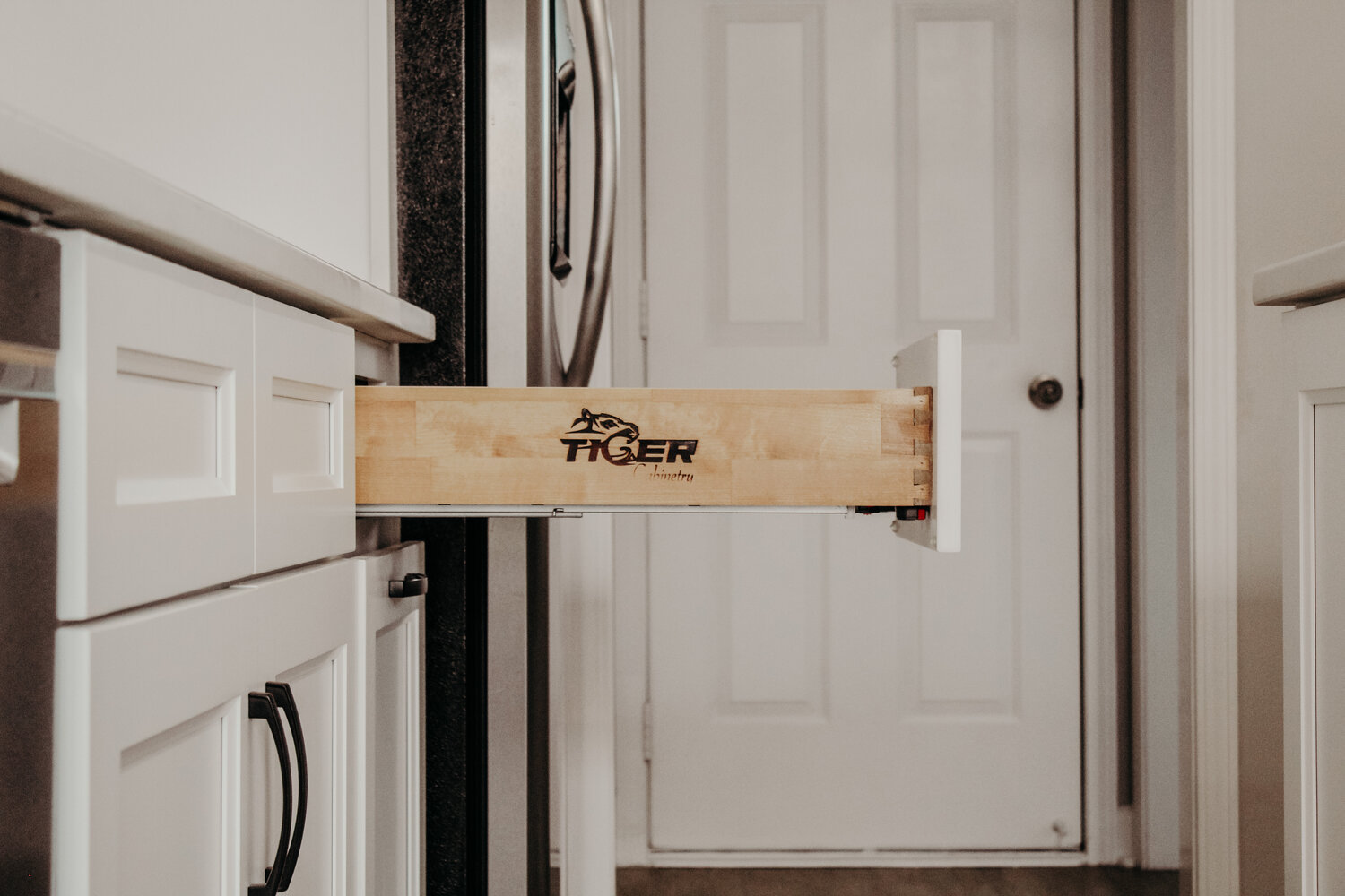 A Tiger Cabinetry drawer box pulled open on full extension runners, branded on the maple side panel