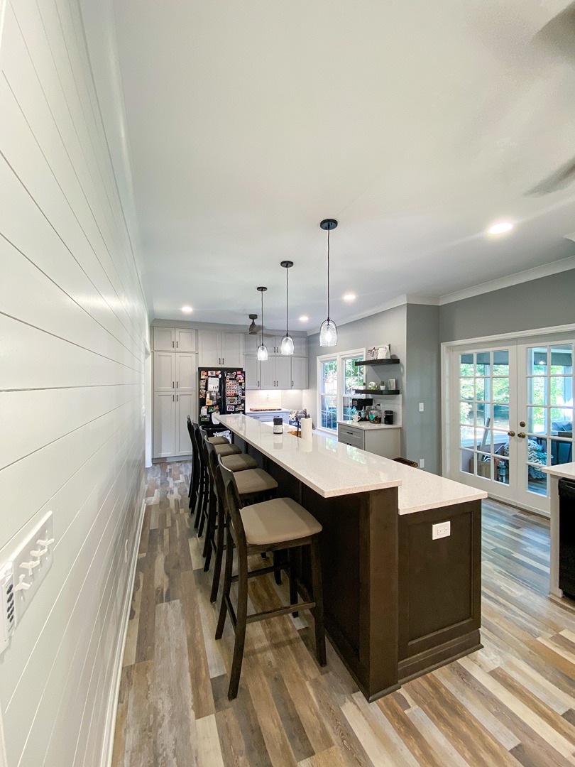 A long dark stained breakfast bar with five stools running the length of an open plan kitchen and living space